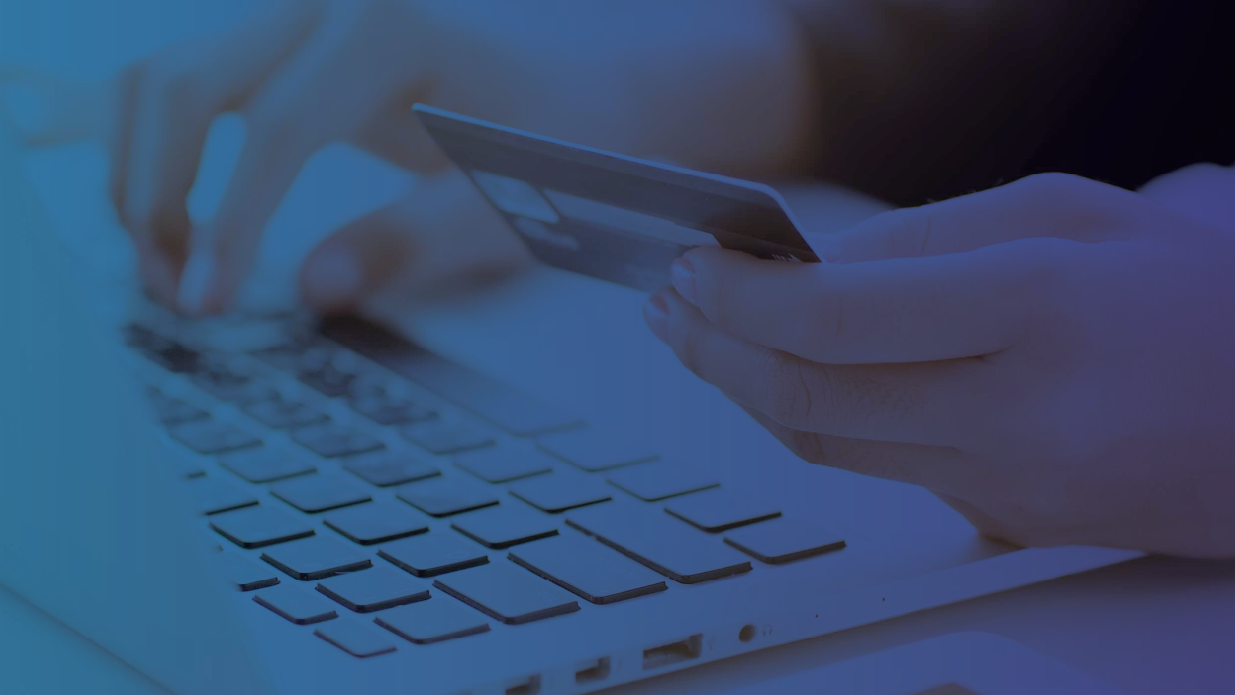 Person holding a credit card while typing on a laptop, representing eCommerce payments and fraud prevention.