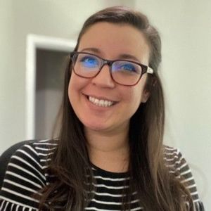 Smiling woman with glasses in a black-and-white striped top.