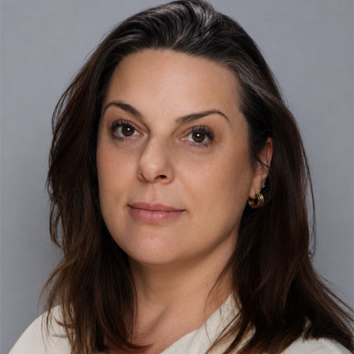 Headshot of a woman with shoulder-length dark hair, wearing a patterned blouse, smiling slightly against a neutral background.
