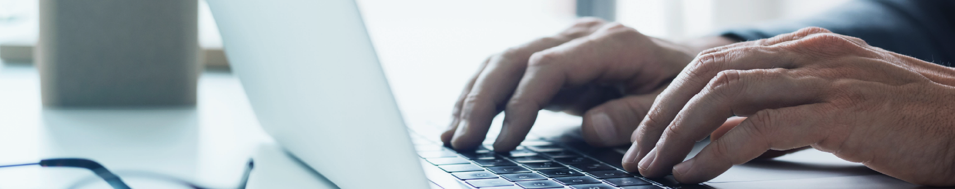 Close-up of hands typing on a laptop keyboard.